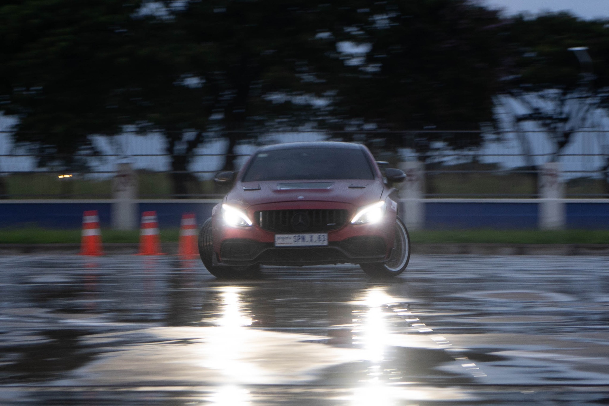 Mercedes C63 headlights on wet track at dusk