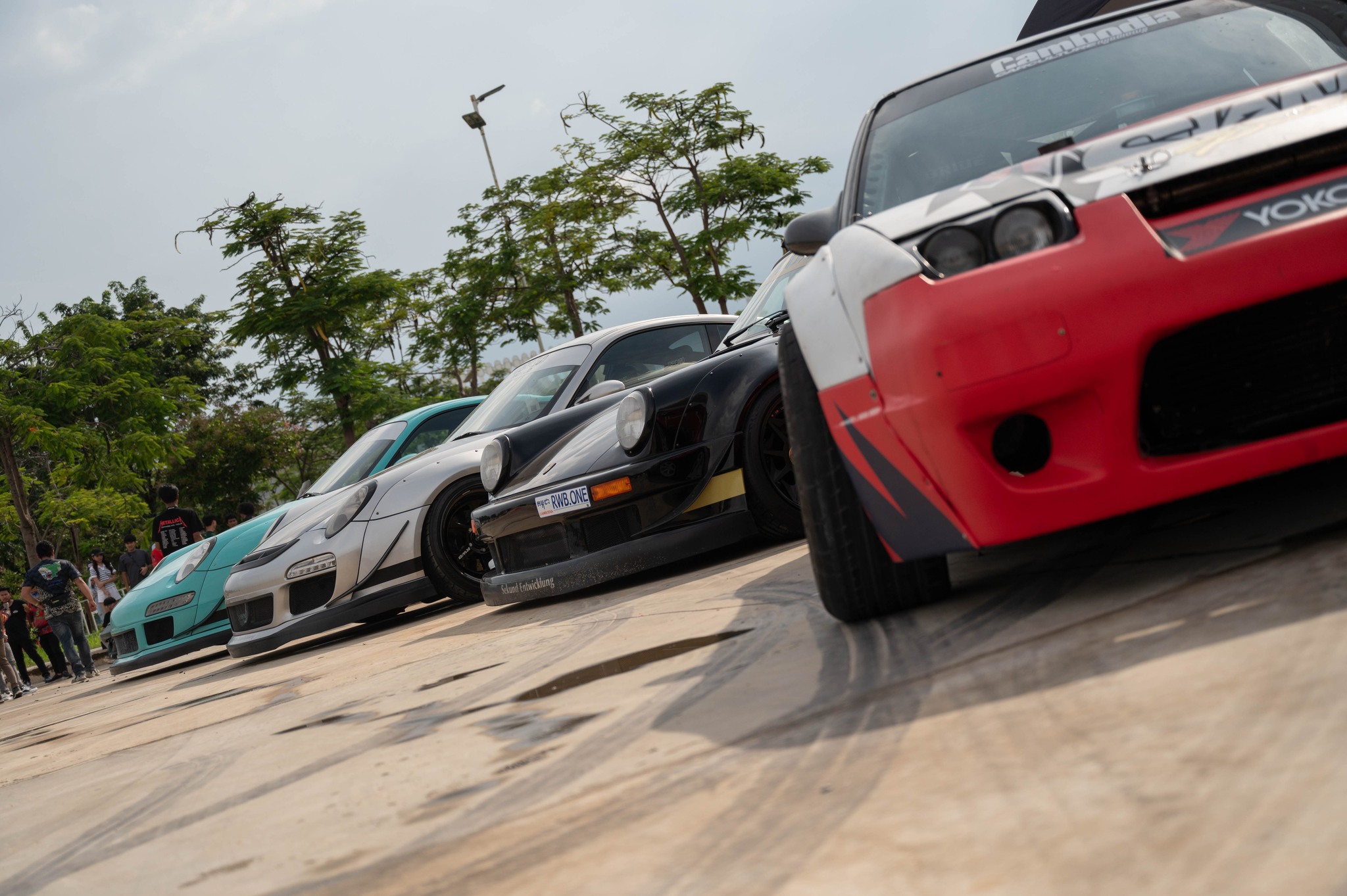 Low-angle view of drift cars and Porsches lined up