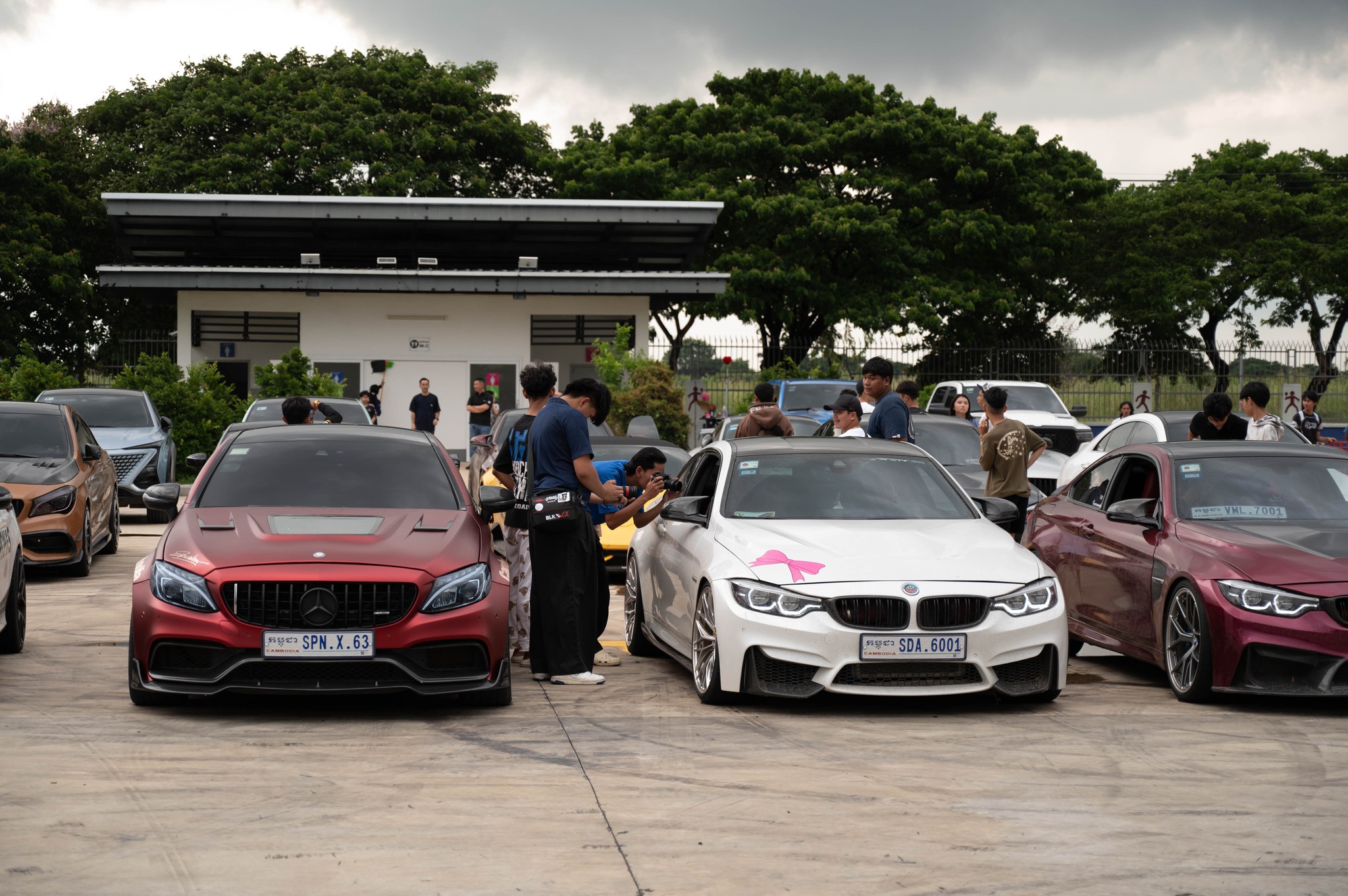 Paddock scene with Mercedes C63, BMW M4s, and crowd