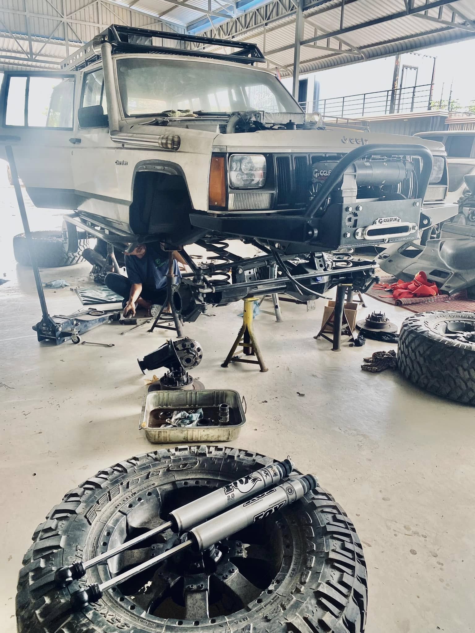 Full Cherokee on jack stands with FOX shocks and mud tires