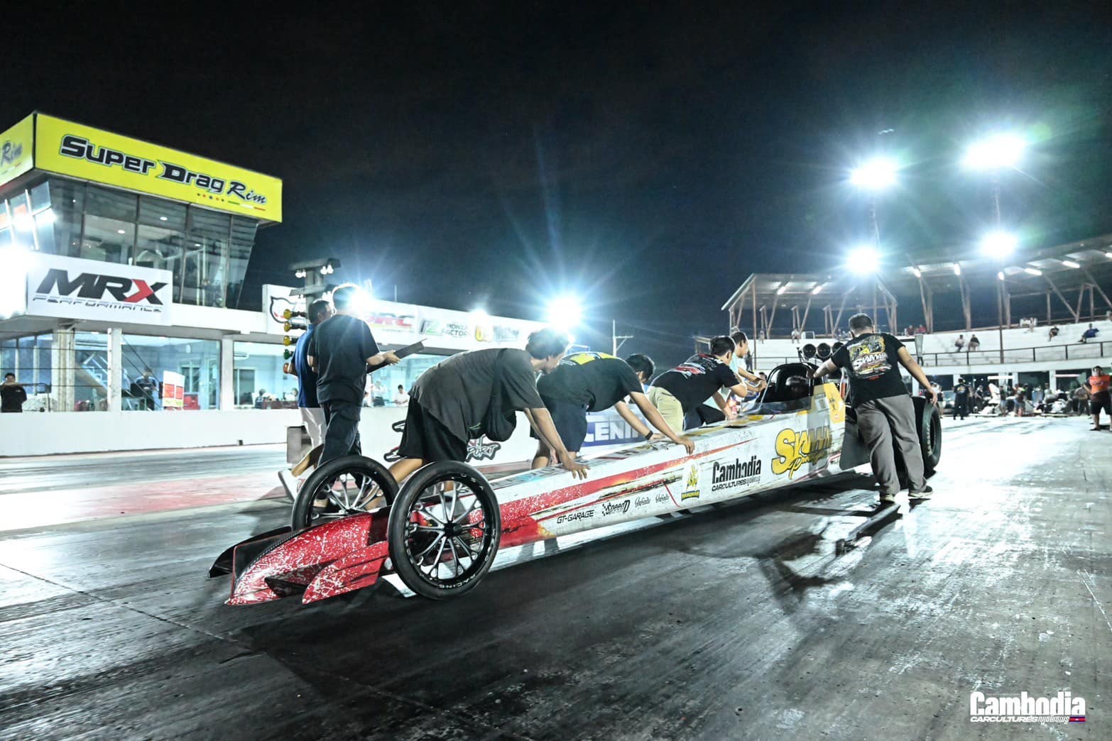 Crew pushing dragster into position